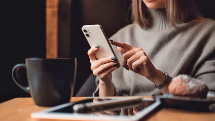 Một người phụ nữ cầm iPhone gần một chiếc iPad.